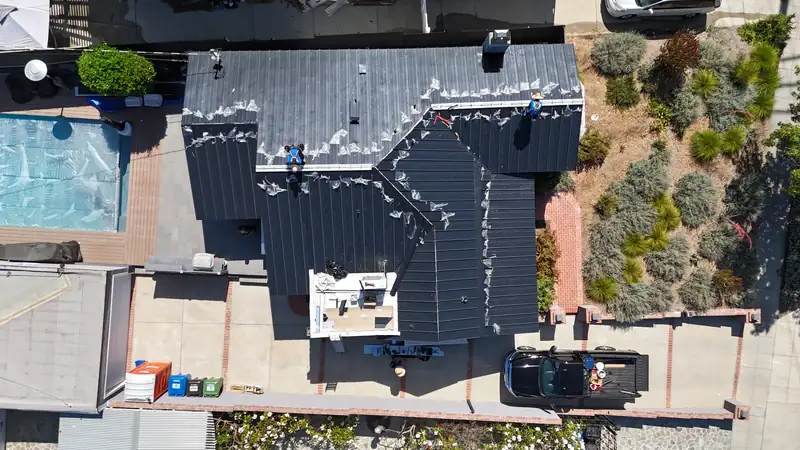 Eclipse crew installing black standing seam panels, seen from directly above, protective film still on